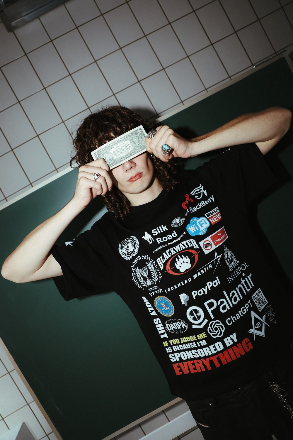 Model in the Sponsored by Everything tee holding a dollar bill across their eyes